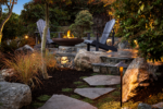 two chairs sit by a fire pit under a leafy tree